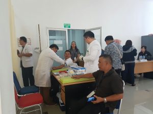 Suharjo Makalalag (kanan) tampak menggunakan kaos berwarna hitam, menunggu diperiksa, karena Dokter masih memeriksa Nayodo Kurniawan.