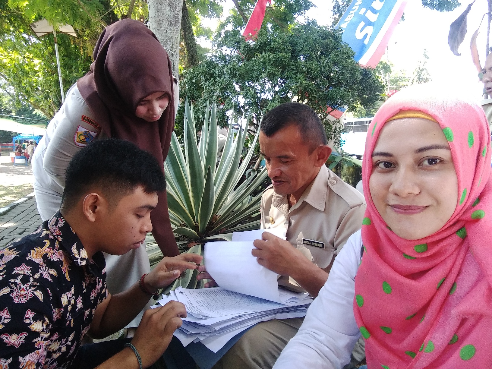 Caption: Om Tam saat melayani ASN yang absen saat peringatan Hari Lansia ke-23 di Lapangan Boki Hotinimbang, Kotamobagu, (foto: Totabuan.News/Neno Karlina).