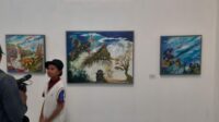 Azka Damara di antara lukisannya dalam pameran seni rupa di Kopi Macan & Art Galery Yogyakarta. Foto: Clementine Roesiani